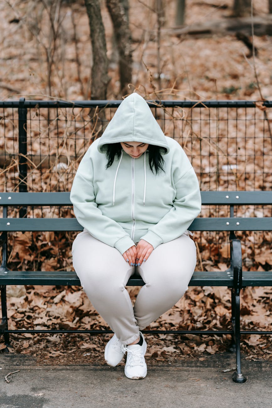 sad woman sitting on bench in autumn park